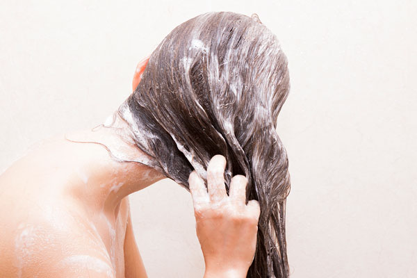 Frau unter der Dusche mit Shampoo in den Haaren